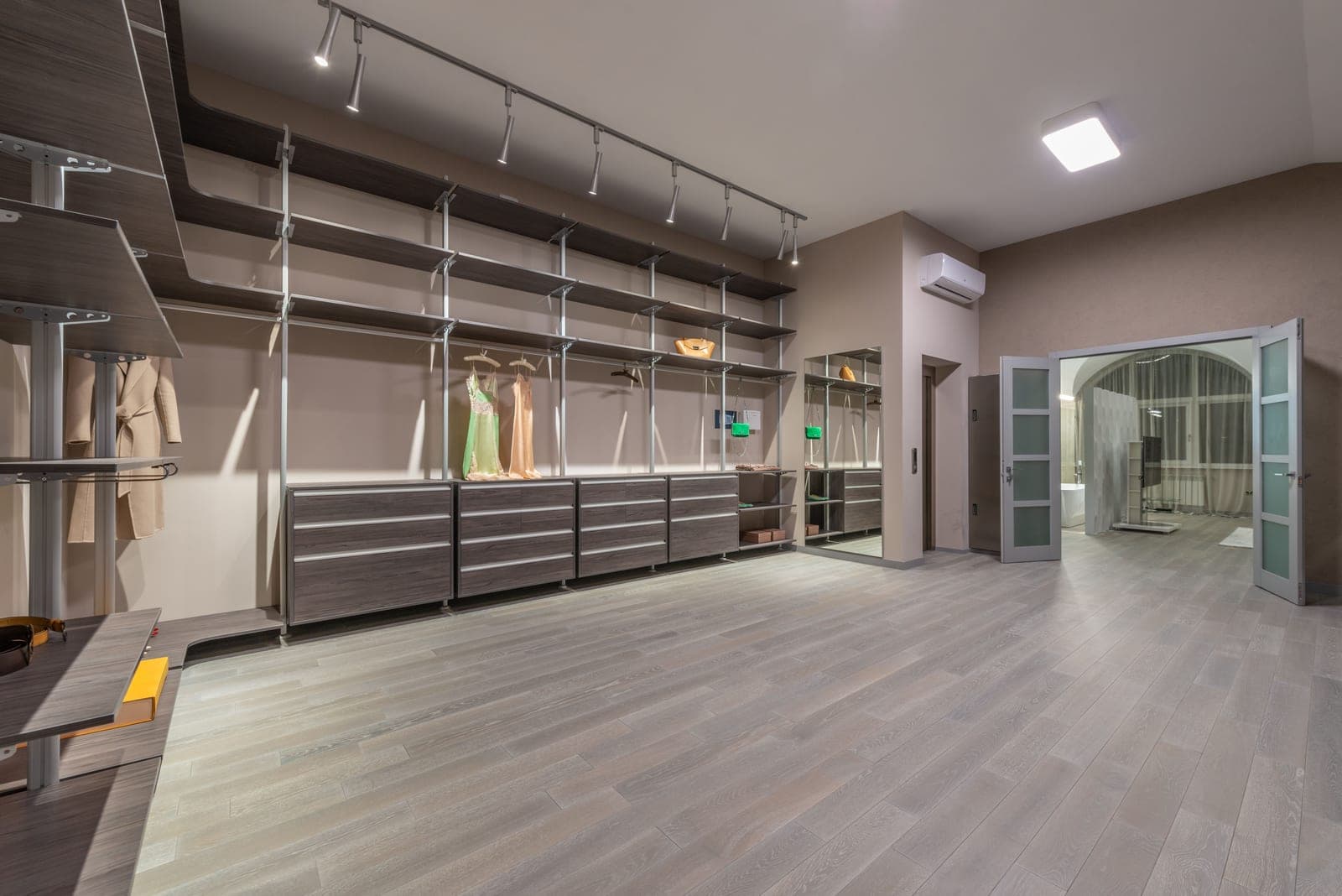 An organized closet with clothes hanging on a rail above folded storage